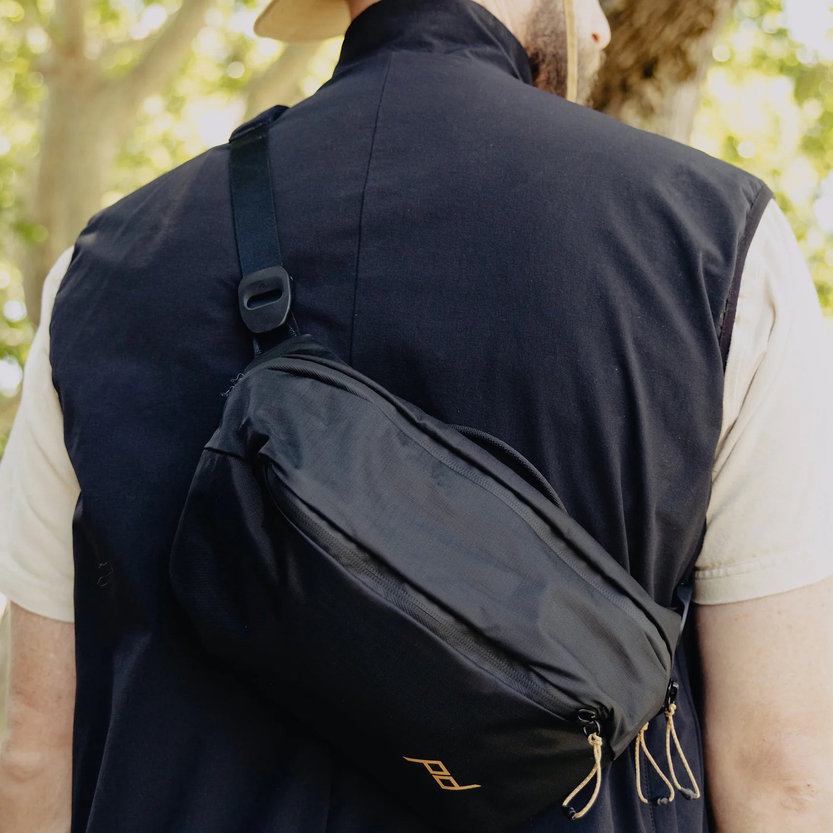 Person wearing a black vest with a matching bag outdoors