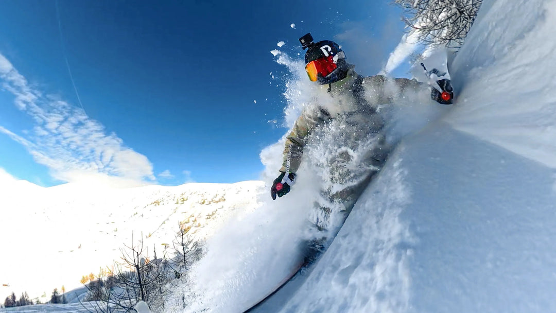Person snowboarding down a snowy slope with a clear blue sky.