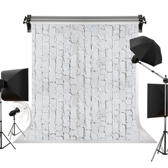 A photography backdrop with a white brick wall pattern, displayed on a stand with studio lighting equipment including softboxes and umbrellas on a white background.