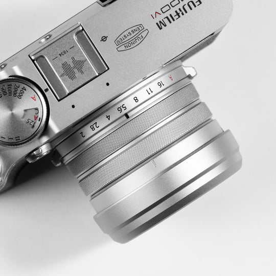 Top-angle close-up of SmallRig silver metal lens hood and adapter ring seamlessly fitted onto a FUJIFILM X100VI camera body.