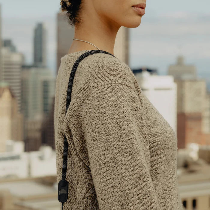 Person wearing a textured beige sweater with a cityscape in the background