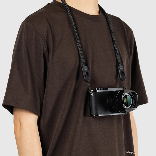Person wearing a camera on a strap over a plain background