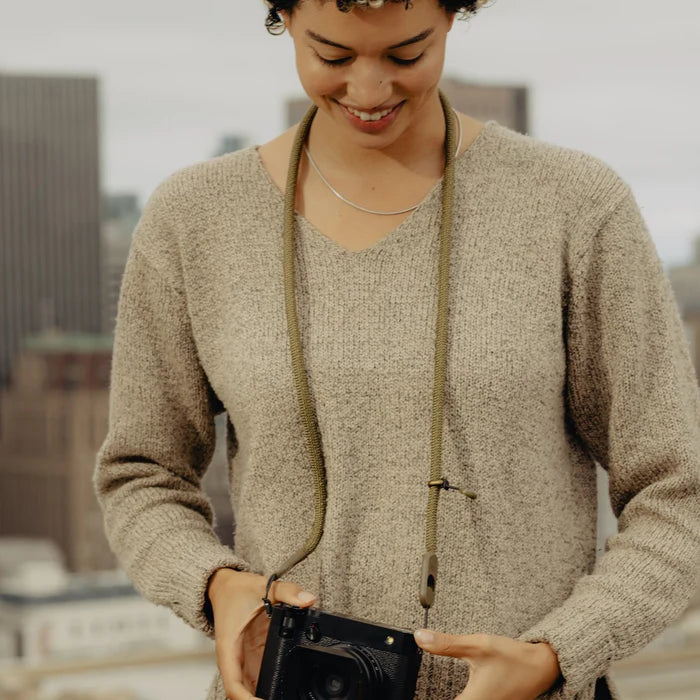 Woman holding a camera with a blurred cityscape in the background