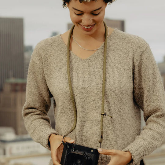 Woman holding a camera with a blurred cityscape in the background