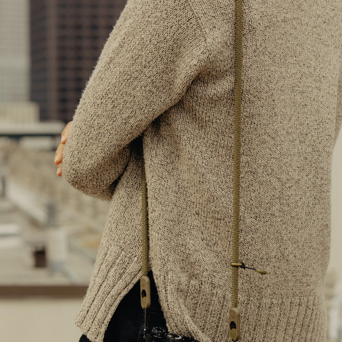Close-up of a person wearing a Peak Design Form Rope Camera Strap with a blurred background