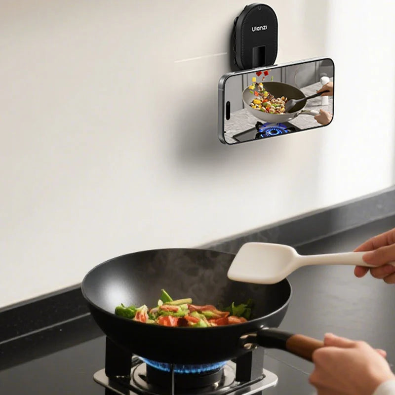 Ulanzi MA39 MagLock suction mount attached to a kitchen wall holding an iPhone displaying a cooking tutorial while preparing food in a wok.