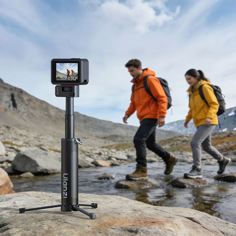 Ulanzi MT98 foldable selfie stick set up as a mini tripod on a rock beside a stream while a couple hikes in the background.